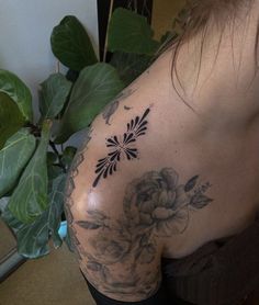 a woman with a flower tattoo on her back and shoulder is looking at the camera