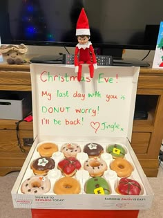 an elf is sitting on top of a box of donuts