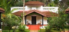 a white house with red steps leading up to the front door and covered in greenery