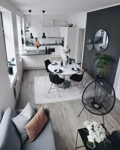 a living room filled with furniture and a white table surrounded by black chairs on top of a hard wood floor