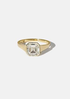 a yellow gold ring with an emerald cut diamond