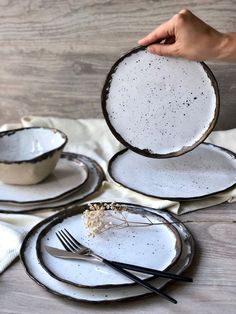 a person is holding an empty white plate with black rims and silverware on it