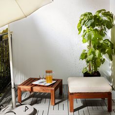 a table with an umbrella on top of it next to a bench and potted plant