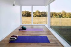 yoga mats on the floor in an empty room with large windows overlooking a grassy field