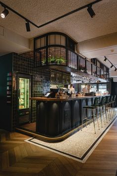 an empty bar with chairs around it in a room that has wooden floors and black walls