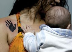 a woman holding a baby in her arms with a hand print on it's chest