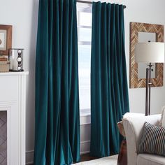 a living room filled with furniture and a window covered in blue velvet drapes next to a fire place