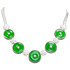 Natural Green Jadeite Jade and Diamond Necklace, gracefully made in 18K White Gold. This necklace holds five individual circular-cut Green Jade disks, with brilliant round-cut diamond floral pieces. Secured with a bezel setting and lobster closure. This floral motif necklace has a substantial weight that sits beautifully on the neck. Item Details: - Type: Necklace - Metal: 18K White Gold - Weight: 40 Grams - Setting: Bezel - Length: 17 Inches ______________________________ Center Stone Details: - Type: Jadeite Jade - Cut: Circular-Cut - Color: Green - Measurements: 18-21 MM (per disk) ______________________________ Side Stone Details: - Type: Natural Diamond - Carat: 2.50 CTTW - Cut: Round - Color: F-G - Clarity: VS1-VS2 - Measurements: 3.5 - 2 MM ______________________________ Luxury Green Round Stone Necklace, Green Gia Certified Fine Jewelry Necklace, Green Round Beads Costume Necklace, Luxury Green Cutdana Necklace, Luxury Collectible Green Necklace, Disc Necklace, Jade Green, Metal Necklaces, Round Cut Diamond