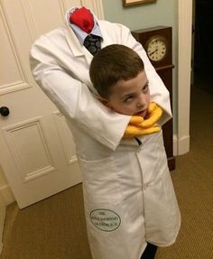 a young boy dressed up as a doctor holding a banana in his hands and wearing a white lab coat