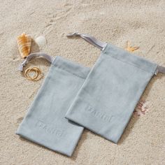 two personalized towels on the beach with rings and seashells in the sand