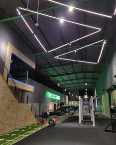 an indoor gym with treadmills, exercise equipment and lights hanging from the ceiling