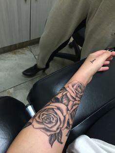 a woman's arm with a rose tattoo on it, sitting in a chair