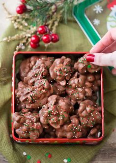 a person is picking up some kind of chocolate covered cookies in a red container with sprinkles