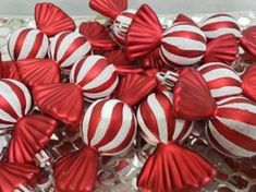 many red and white ornaments are in a glass bowl on the table, with silver sequins around them