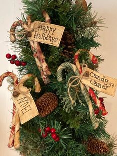 a christmas tree decorated with pine cones, candy canes and holiday tags that say happy holidays