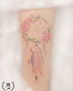 a woman's leg with a tattoo on it that is decorated with flowers and feathers