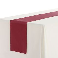 a red and white table runner on top of a bed