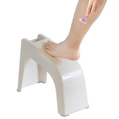 a woman's foot on top of a white stool