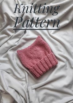 a pink knitted sweater laying on top of a white bed with the words knitting pattern