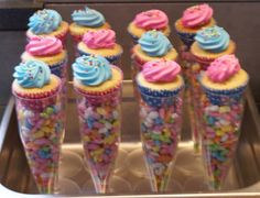 cupcakes with frosting and sprinkles are arranged in cones on a tray