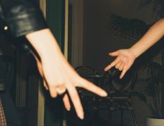 two hands reaching out towards each other in front of a table with chairs and potted plants