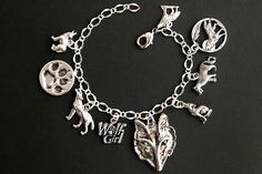 "A collection of silver plated wolf themed charms have been dispersed around a shimmering silver plated bracelet chain in this handmade charm bracelet. This wolf girl charm bracelet is then completed with a lobster clasp and a 1/2 inch of chain at the end for adjustable sizing. Charms in this bracelet include a wolf and the moon charm, a wolf head charms, five wolf charms, a paw print charm, and a \"wolf girl\" charm. ● Sizing ● To determine your bracelet size, do a snug measurement of your wris Silver Wolf Design Stainless Steel Jewelry, Silver Stainless Steel Wolf Jewelry, Silver Stainless Steel Wolf Design Jewelry, Sterling Silver Wolf Design Jewelry, Silver Symbolic Wolf Design Jewelry, Symbolic Silver Wolf Design Jewelry, Silver Wolf Design Symbolic Jewelry, Themed Silver Stainless Steel Jewelry, Themed Silver Jewelry For Gifts