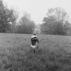 black and white photograph of a person walking through a field