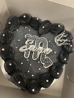 a black heart shaped cake with white frosting and the word happy written on it