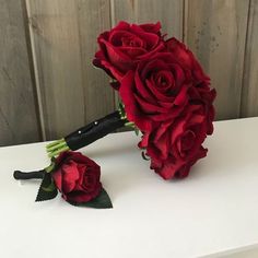 a bouquet of red roses sitting on top of a white table next to a knife