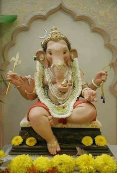 an elephant statue sitting on top of a wooden platform in front of a flower covered wall