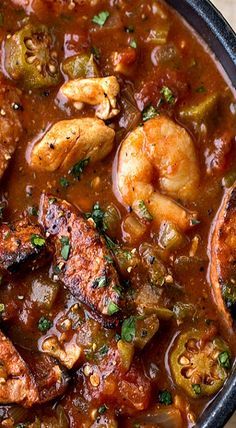 a black bowl filled with shrimp and vegetable stew