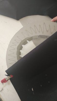 a person is cutting paper with a circular sawtoothing tool on top of it