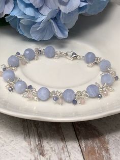 "The Hydrangea Bracelet. This luxurious piece features AAA Blue Lace Agate with beautiful swirls of powdery sky blue. Clusters of AAA periwinkle Tanzanite, creamy freshwater Pearls, white topaz and petal pink rose quartz cascade between each blue lace agate. All gemstones are faceted for maximum sparkle and shine, and everything is intricately wrapped in your choice of 14kt yellow gold filled, 14kt rose gold filled or sterling silver. A highly polished lobster claw clasp completes the design. Th Cheap Blue Gemstone Beaded Bracelets, Elegant Faceted Beads Crystal Bracelet, Cheap Blue Bracelets With Polished Beads, Cheap Blue Pearl Bracelets, Luxury Blue Faceted Beads Bracelets, Light Blue Beaded Bracelets, Blue Pearls, Light Blue Bracelet, Blue Lace Agate Jewelry