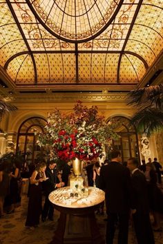 a table topped with lots of food and flowers in front of a glass dome ceiling