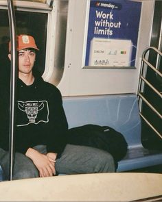 a man sitting on a train seat with his hat on