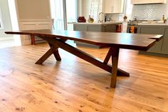 a wooden table sitting on top of a hard wood floor in a kitchen next to an oven