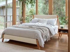 a bed sitting in the middle of a bedroom next to a wooden table and windows