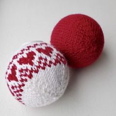 two red and white knitted balls sitting next to each other