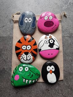 four painted rocks with different animals on them sitting on a piece of cloth next to each other