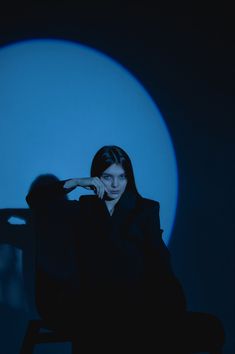 a woman sitting in a chair with her hand on her head