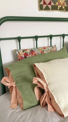 a green metal headboard with two pillows on top of it and an old quilt hanging above the bed