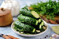 a white plate topped with cucumbers on top of a table next to garlic