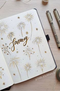 an open notebook with the word january written in gold on it next to some markers and crayons