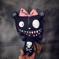 a hand holding up a black cat with teeth and fangs on it's face