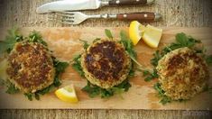 three crab cakes on a cutting board with lemon wedges and knife next to them