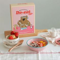 a bowl of cereal with strawberries and yogurt next to a box of do - egg