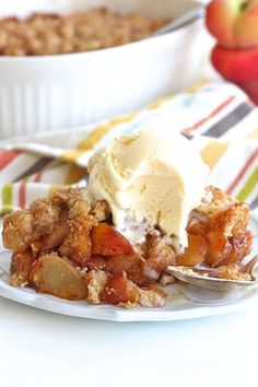 a white plate topped with fruit cobbler next to a bowl of ice cream and an apple