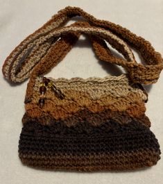 This crocheted cross bag is shaded in browns from beigel to dark brown. It closes with a zipper which is adorned with a charm of glass beads attached with a lobster clasp. The small bag is fun and has a variety of uses. The bag is approx. 8 inches long by 6 inches wide.  The bag drop is 23 inches Hand wash and dry on delicate for best results. Brown Crochet Shoulder Bag As Gift, Brown Crochet Shoulder Bag For Gift, Bohemian Brown Crochet Shoulder Bag For Gifts, Brown Crochet Bag For Gift, Crochet Brown Shoulder Bag Gift, Crochet Brown Shoulder Bag For Gift, Brown Crochet Crossbody Bag For Daily Use, Brown Crochet Shoulder Bag Gift, Brown Crochet Bags For Gifts