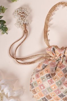 a small purse with pearls on it next to flowers