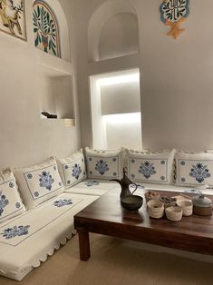 a living room filled with white couches covered in blue and white pillows on top of a wooden table